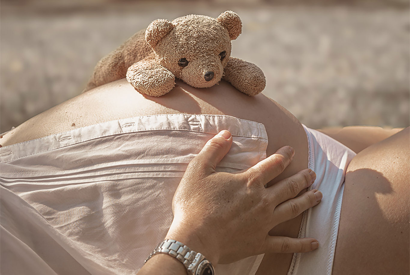 photo d'un ventre de grossesse avec un nounours dans la nature